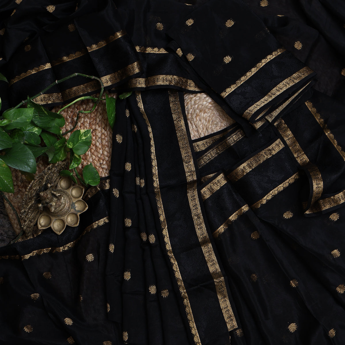 Black saree with gold embroidery and a woven basket in the background