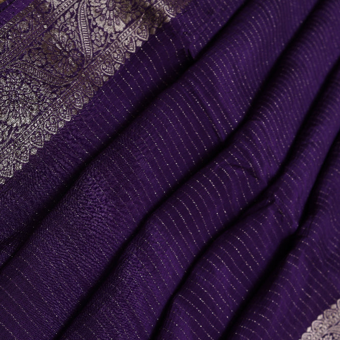 Purple saree with intricate silver patterns on a textured surface