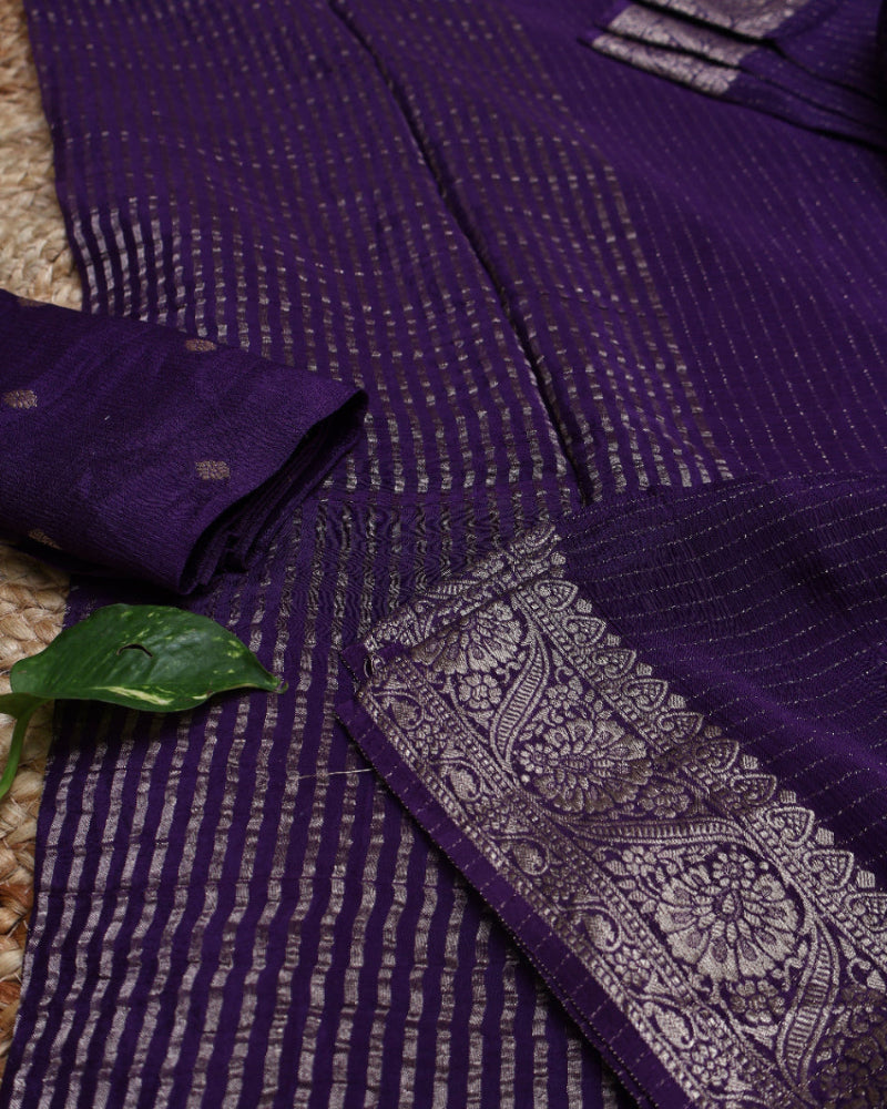 Close-up of a purple saree with intricate patterns and a green leaf.