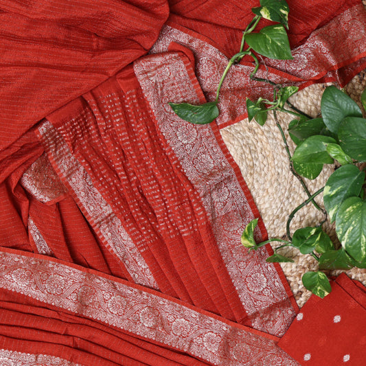 orange saree with  silver lines and green leaves on a textured surface